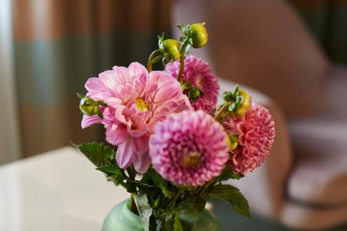 a bunch of pink flowers in a glass vase at Hotel Metropol by Maier Privathotels in Munich