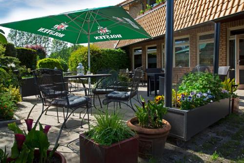 a patio with a table and chairs and an umbrella at Hotel Kreuzer in Wedel