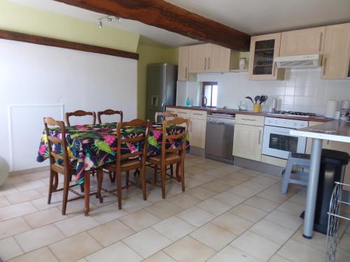 - une cuisine avec une table, des chaises et une cuisinière dans l'établissement La ciboulette, aux Loges