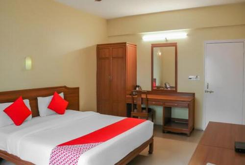 a bedroom with a bed with red pillows and a desk at Hotel Nandanvan Annexe in Pune