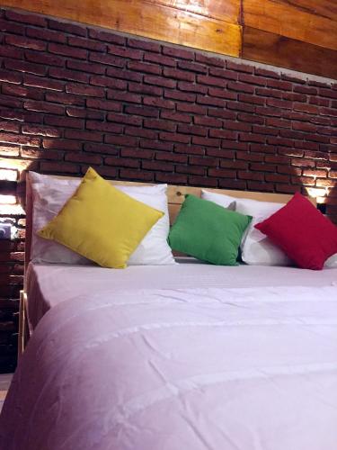 a white bed with four colorful pillows on it at Fair View Cottage in Ella