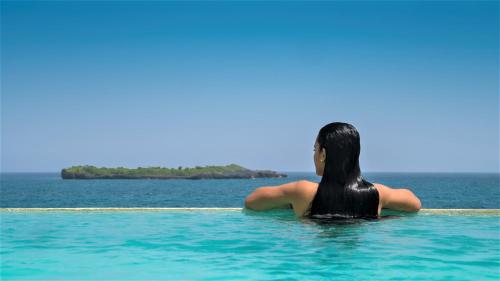 a woman sitting in the water looking at the ocean at Cap el Limon Luxury Villas in El Limón