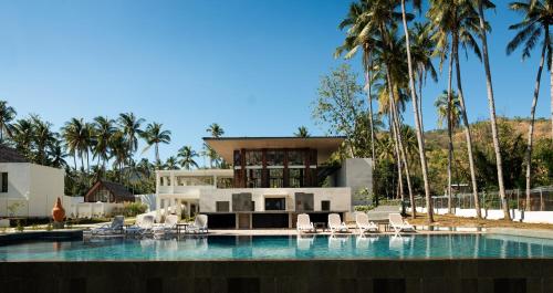 dom z basenem i palmami w obiekcie The Kayana Beach Lombok w mieście Senggigi