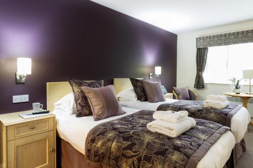 a hotel room with two beds with towels on them at Burntwood Court Hotel in Barnsley