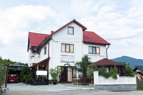 a white house with a red roof at Pensiunea Rozmarin in Sîngeorz-Băi