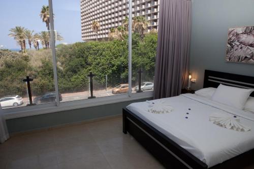 a bedroom with a bed and a large window at Liber Apartments BY RAPHAEL HOTELS in Tel Aviv