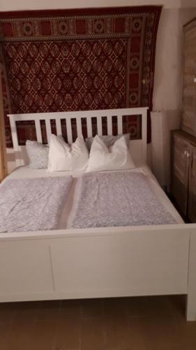ein weißes Bett mit zwei Kissen und einem Kopfteil in der Unterkunft Remete-lak in Villány