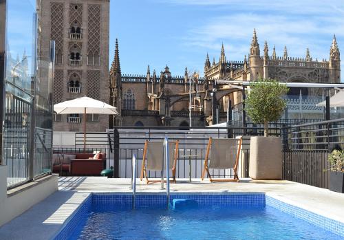 two chairs sitting in a swimming pool in front of a building at EME Catedral Hotel in Seville