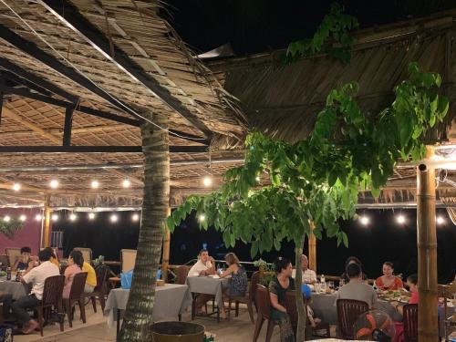 a group of people sitting at tables in a restaurant at Song Ngư Riverside Homestay in Can Tho