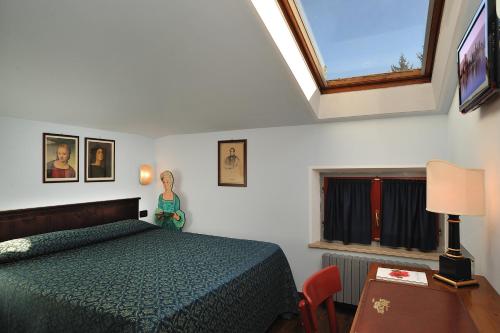 Schlafzimmer mit einem Bett, einem Tisch und einem Fenster in der Unterkunft Hotel Bonconte in Urbino
