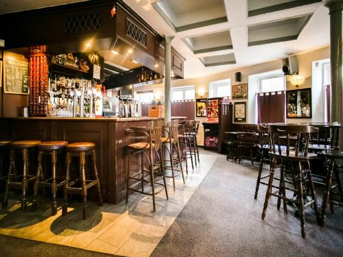 a bar with wooden stools in a restaurant at Corner Hotel in Carnoustie