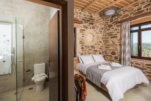 a stone walled bedroom with a bed and a toilet at Lameriana Luxury Village in Lamerianá