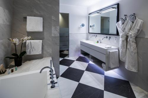 uma casa de banho com piso em xadrez preto e branco em Hotel München Palace em Munique