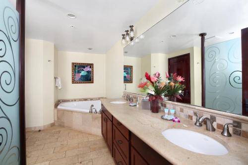 a bathroom with two sinks and a tub and a large mirror at Waipouil Beach Resort Gorgeous Ocean Front Condo! Sleeps 8 AC Pool in Kapaa