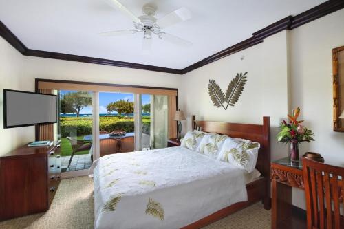a bedroom with a bed with a ceiling fan and a television at Waipouil Beach Resort Gorgeous Ocean Front Condo! Sleeps 8 AC Pool in Kapaa