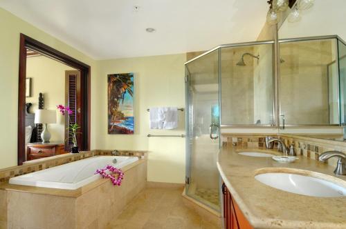 a bathroom with two sinks and a tub and a shower at Waipouli Beach Resort Penthouse Exquisite Ocean & Pool View Condo! in Kapaa