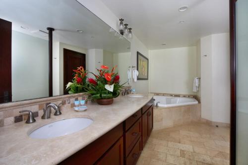 ein Badezimmer mit einem Waschbecken und einem großen Spiegel in der Unterkunft Waipouli Beach Resort E404 - PENTHOUSE Ocean & Pool View Jewel - AC in Kapaa
