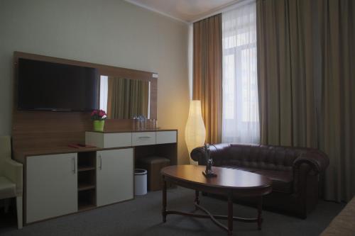 Habitación de hotel con sofá, mesa y TV en Alva Donna Hotel, en Kotelniki