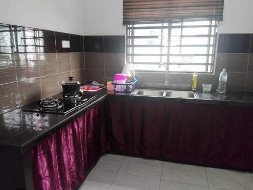 cocina con fregadero y fogones horno superior en Nurul Homestay en Kepala Batas