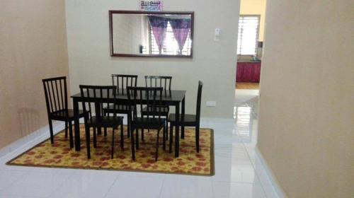 a dining room with a table and chairs on a rug at Nurul Homestay in Kepala Batas