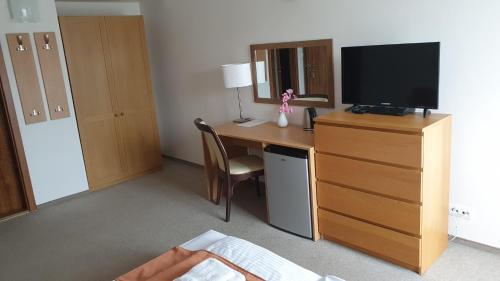 a hotel room with a desk with a television and a bed at Penzión Dubo in Liptovský Mikuláš