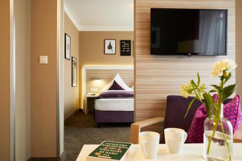 a hotel room with a bed and a tv on a wall at Hotel Mirabell by Maier Privathotels in Munich