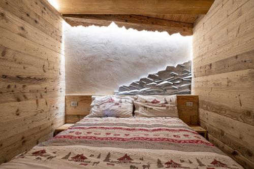 Cama en habitación con pared de madera en Amelu' en Ostana