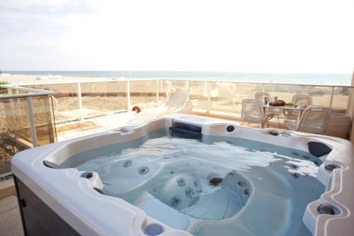 un bain à remous sur un balcon avec une plage dans l'établissement Grand Hôtel Les Flamants Roses Thalasso & Spa, à Canet
