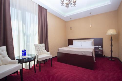 Habitación de hotel con cama, mesa y sillas en Marionn Hotel, en Tiflis