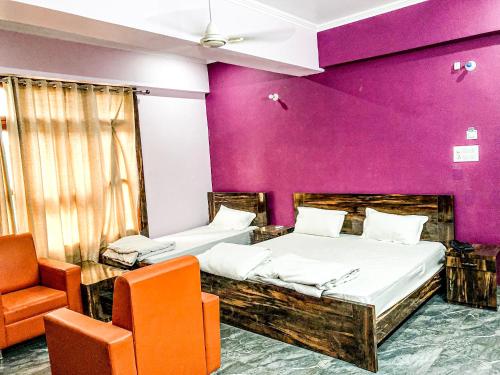 two beds in a room with a purple wall at Hotel Kunti International in Lucknow