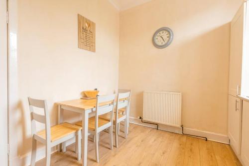 a dining room with a table and chairs and a clock at Arran View in Prestwick