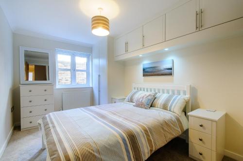 a white bedroom with a bed and a dresser at Beach Retreat Broadstairs in Broadstairs