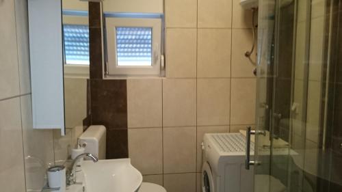 ein Badezimmer mit Waschbecken und Toilette und einem Fenster in der Unterkunft Apartman Marin in Šilo