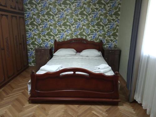 a wooden bed in a room with blue flowers at Nino's Holiday guesthouse in Borjomi