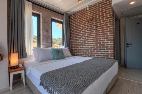 a bedroom with a brick wall and a bed at Sukha Cunda Otel in Cunda