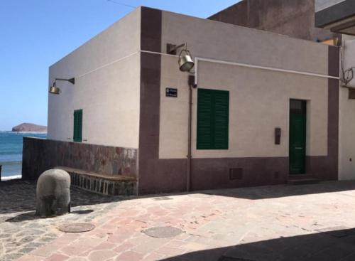 a building with green doors and a bench next to the ocean at Casa El Picacho in El Médano