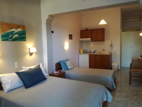una camera d'albergo con due letti e una cucina di Maria Studios a Patitiri