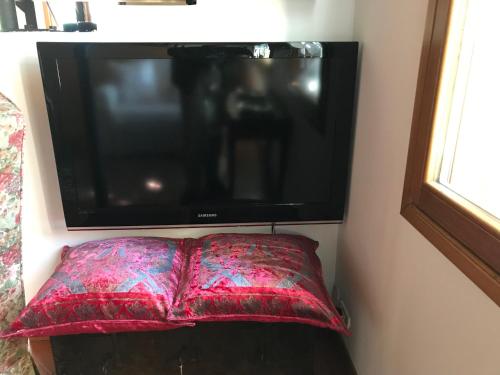 a flat screen tv hanging on a wall with a pillow at Maison Claudià al Lido di Venezia in Venice-Lido