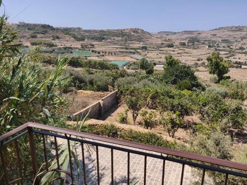 a balcony with a view of a field with trees at The Loft Gozo in Xagħra