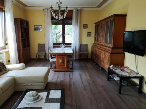 uma sala de estar com um sofá branco e uma televisão em La Casa Dei Nonni em Bussoleno
