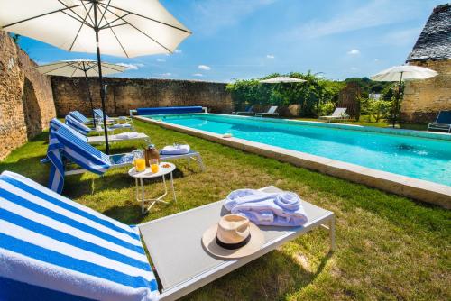 - une piscine avec des chaises, une table et un parasol dans l'établissement Hôtel du Domaine de La Groirie - Le Mans, à Trangé