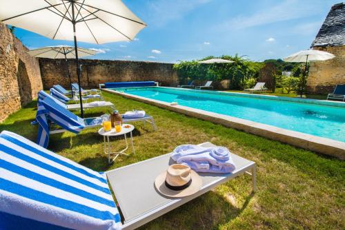 - Piscina con sillas, mesa y sombrilla en Hôtel du Domaine de La Groirie - Le Mans en Trangé