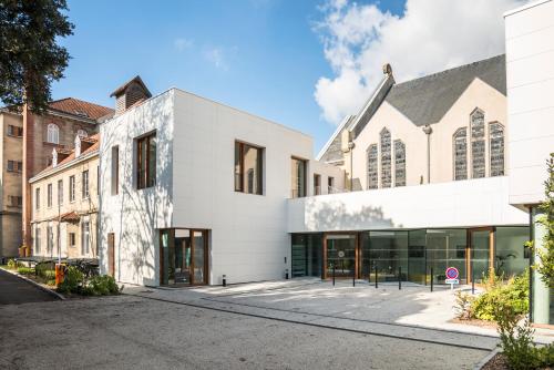 a large white building with glass doors on a street at Hotel Saint Louis Beaulieu - Bordeaux in Bordeaux