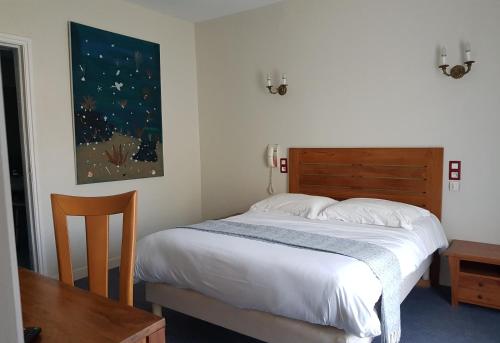 - une chambre avec un lit doté d'une tête de lit en bois et d'une table dans l'établissement Hotel Pyrenées Atlantique, à Saint-Pée-sur-Nivelle