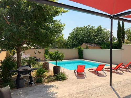 una piscina con sillas rojas y sombrilla en La Maison de Caillette, en Camaret-sur-Aigues