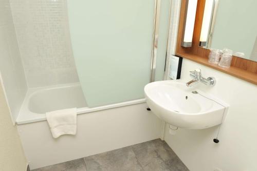 a white bathroom with a sink and a shower at Campanile NATURE - Bordeaux Sud Pessac in Pessac