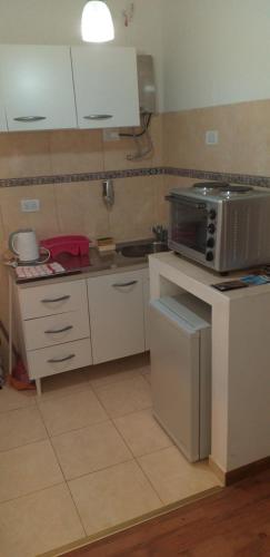 a kitchen with white cabinets and a microwave at Ignacio Garzón Departamento in Córdoba