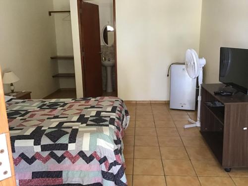 1 dormitorio con 1 cama, TV y nevera en La Casa de Jessy, en Máncora