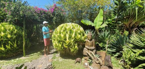 a man standing in a garden next to a statue at Hotel ECOLODGE LE RAVORAHA in Sainte Marie