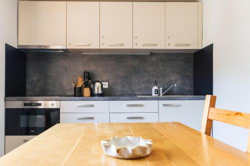 a kitchen with white cabinets and a wooden table at Penzion U Kaplicky in Železná Ruda